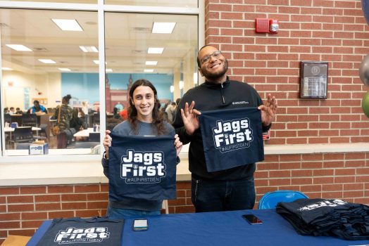 A man and woman hold up shirts that read Jags First.