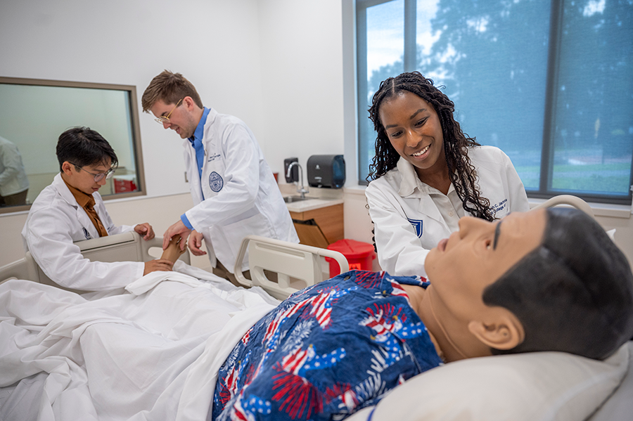 Three medical students use a mannequins to learn how to administer certain tests.