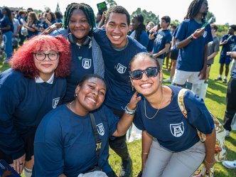 Five college students huddle together outside during a big event.