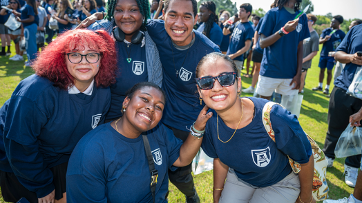 Five college students huddle together outside during a big event.