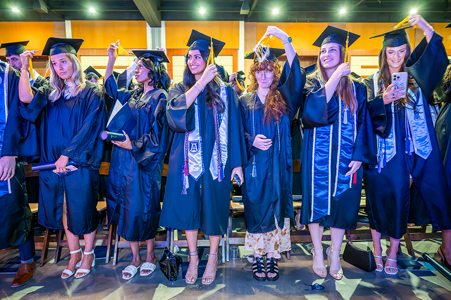 College graduates move the tassels of their graduation caps from right to left during a graduation ceremony.