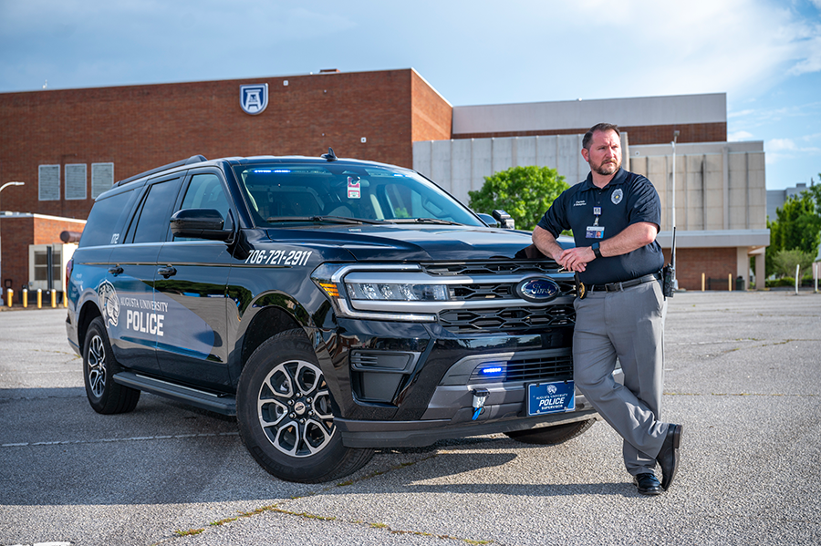 A police officer poses with his patrol vehicle.