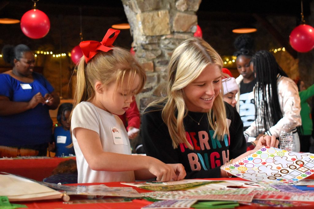 A young girl and a woman work on Christmas arts and crafts.