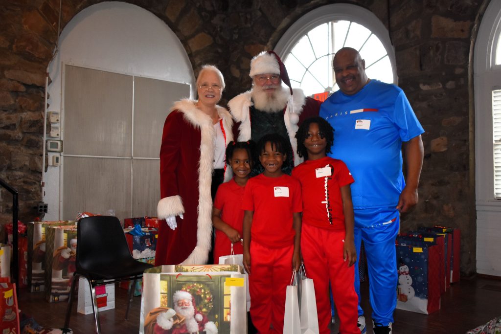 Three young children and their grandfather meet Santa and Mrs. Claus.