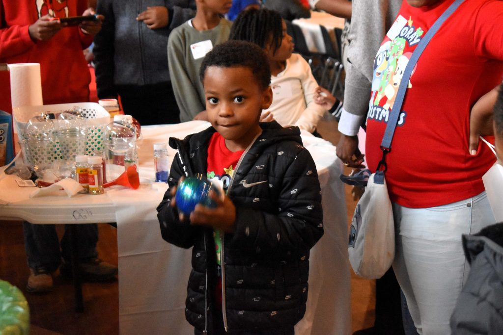 A male child holds a homemade ornament.