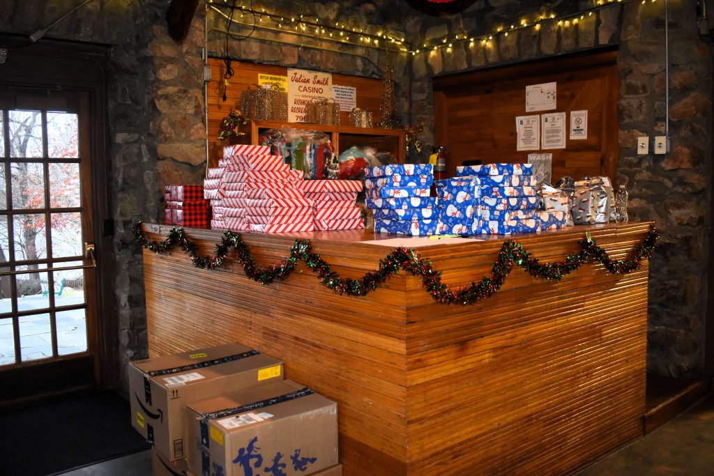 Wrapped Christmas gifts are stacked on a table top.