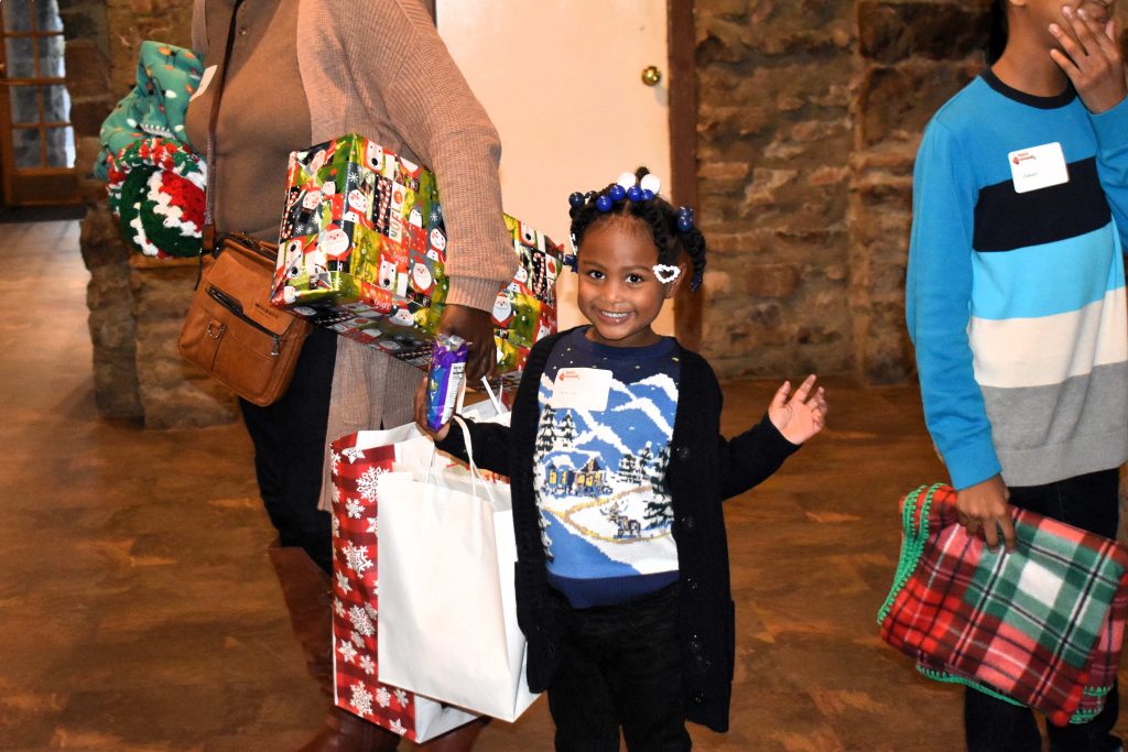 A young girl helps carry Christmas gifts.