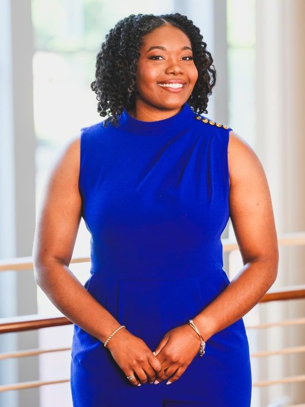 A woman in a blue dress smiles for a photo. 