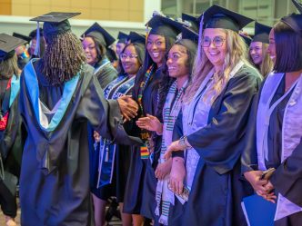 Various students in graduation robes are smiling.