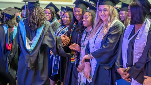 Various students in graduation robes are smiling.