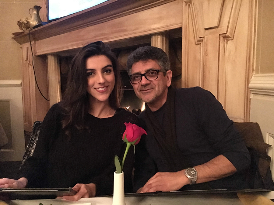 A woman and her father sit at a table in front of a fireplace. They are both holding menus.