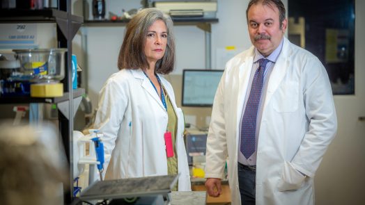 A man and woman in lab coats stand together in a scientific lab.