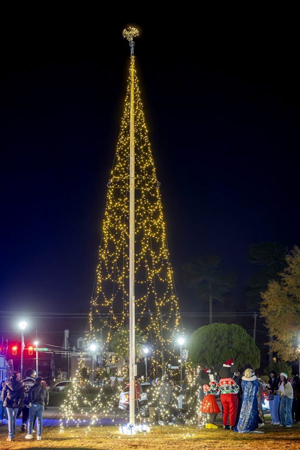 People standing around a lit Christmas tree