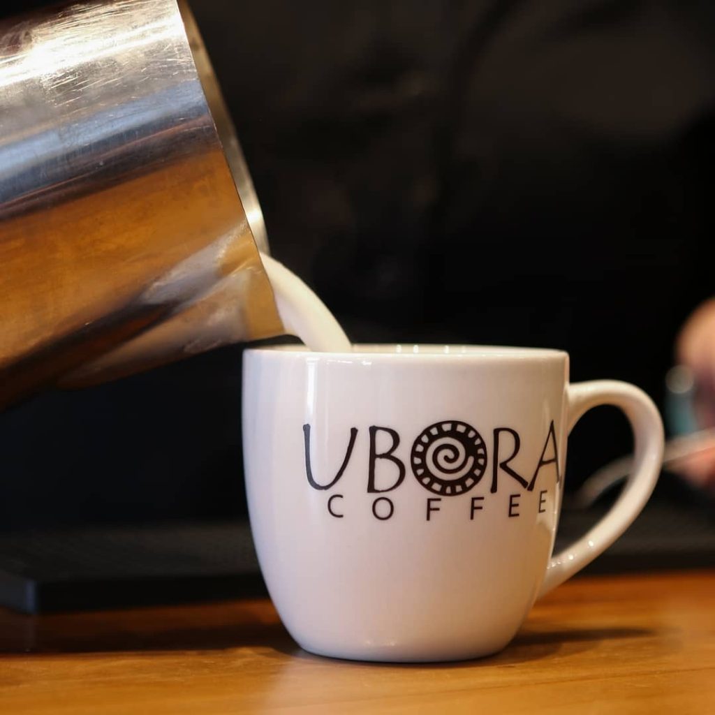 Pouring milk into a coffee cup.