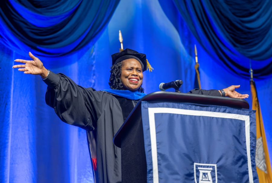 Woman speaks at podium with her arms wide open. 