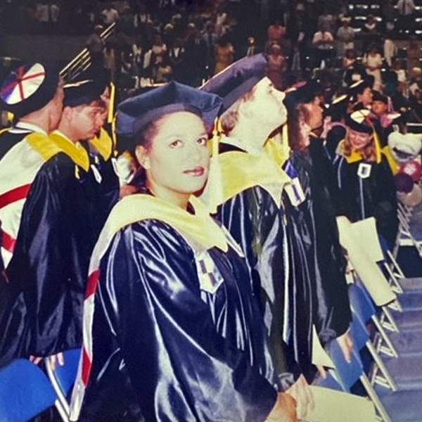 An old photo of college graduates at a graduation ceremony inside a large arena.