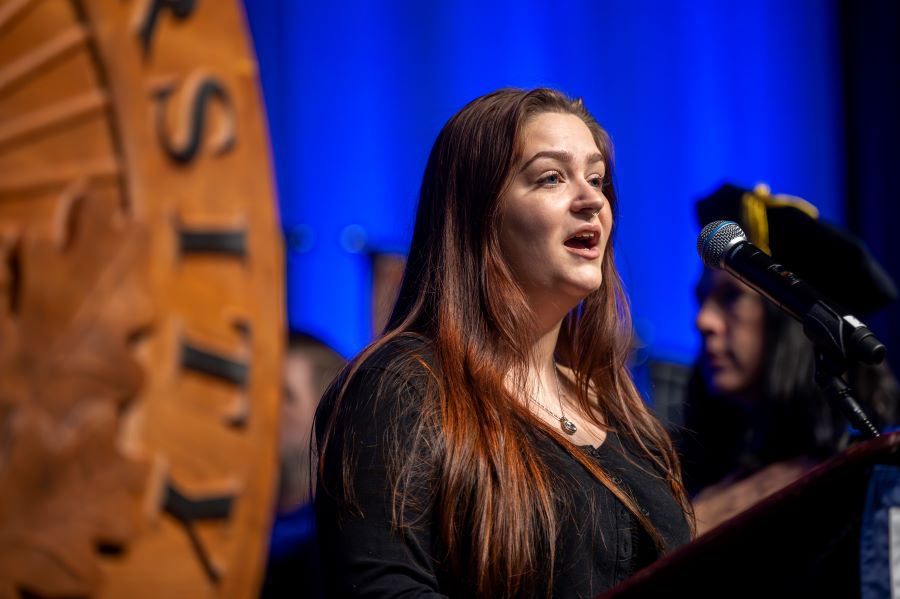 Female student sings at podium. 