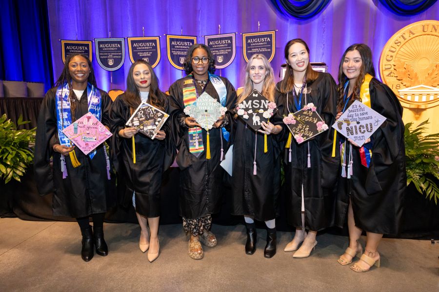 Six female students holding decorated graduation caps. 