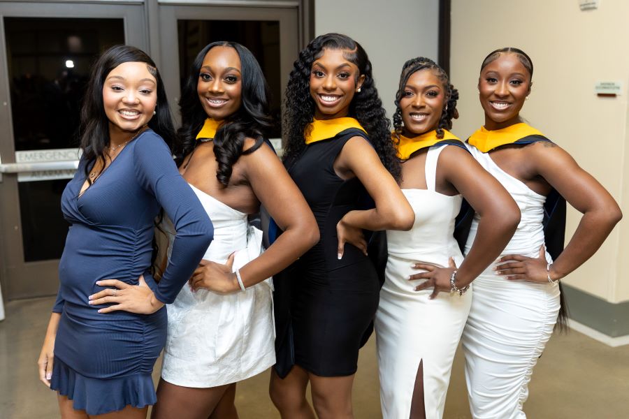 Five female students gather together with their left hand on their hip.