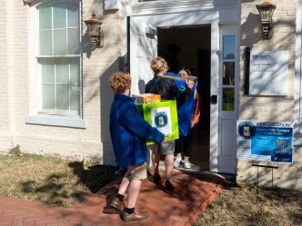 A woman and young boy walk into a building holding boxes.