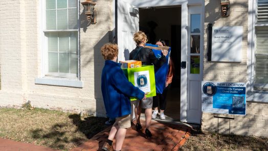 A woman and young boy walk into a building holding boxes.