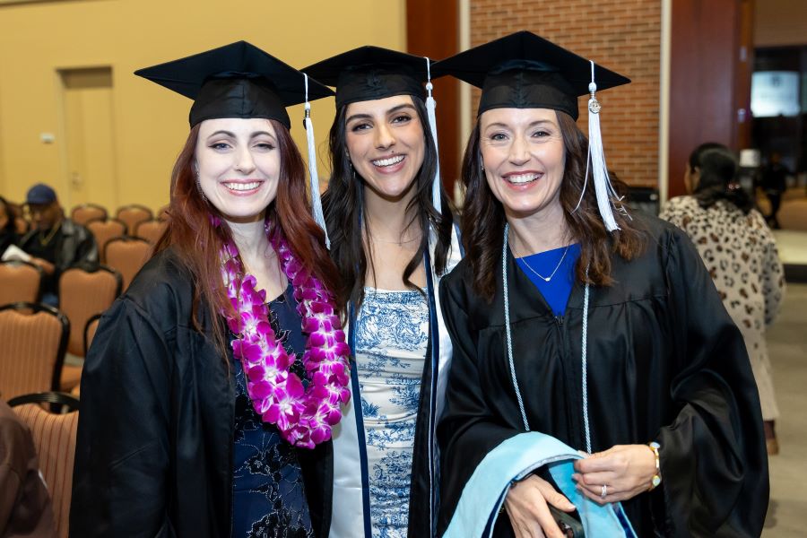 Three female students standing and smiling together. 