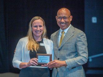 A woman holds up an award plaque while standing next to a man.