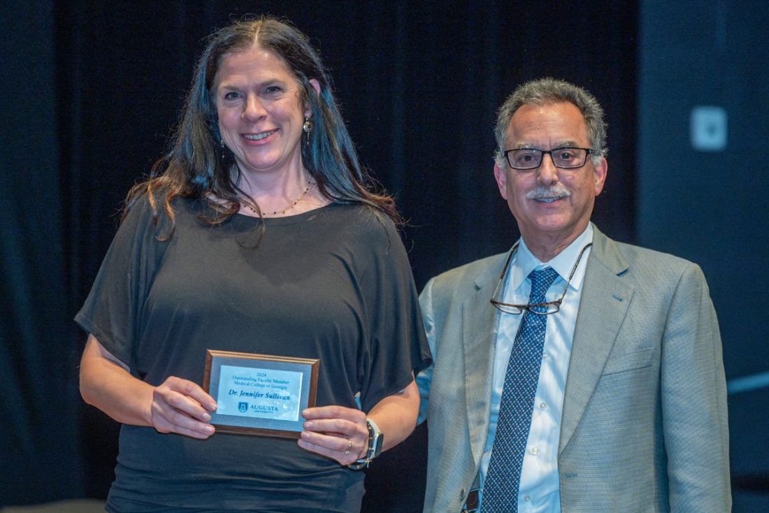 a woman holds an award while a man stands beside her