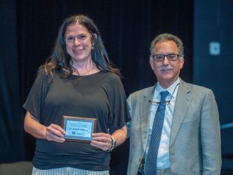 a woman holds an award while a man stands beside her