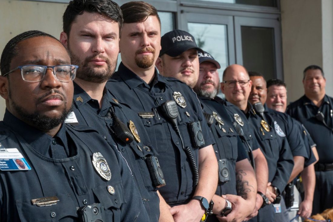 Police officers stand in a line outside.