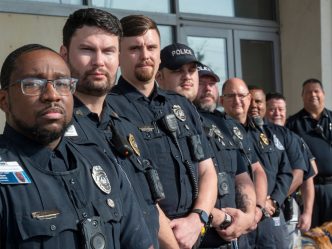 Police officers stand in a line outside.