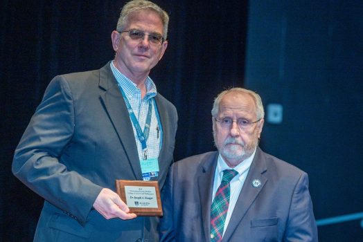 two men stand together while one man holds a plaque