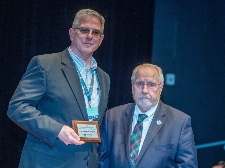 two men stand together while one man holds a plaque