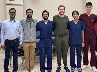 Eight medical students and medical instructors in a line, smiling at the camera.