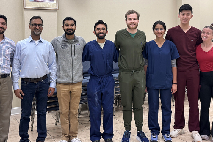 Eight medical students and medical instructors in a line, smiling at the camera.