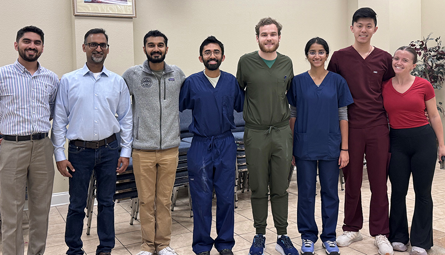 Eight medical students and medical instructors in a line, smiling at the camera.