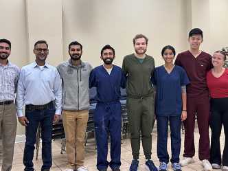 Eight medical students and medical instructors in a line, smiling at the camera.