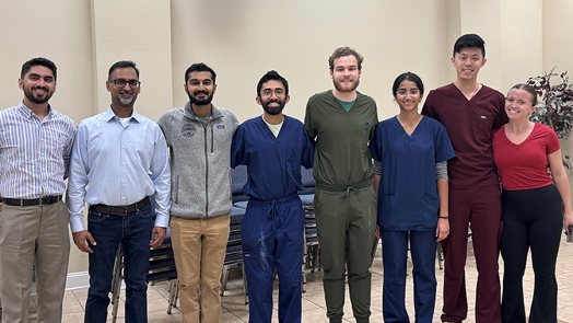 Eight medical students and medical instructors in a line, smiling at the camera.