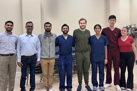 Eight medical students and medical instructors in a line, smiling at the camera.