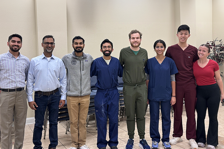 Eight medical students and medical instructors in a line, smiling at the camera.