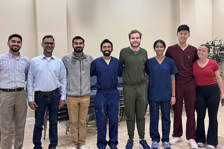 Eight medical students and medical instructors in a line, smiling at the camera.