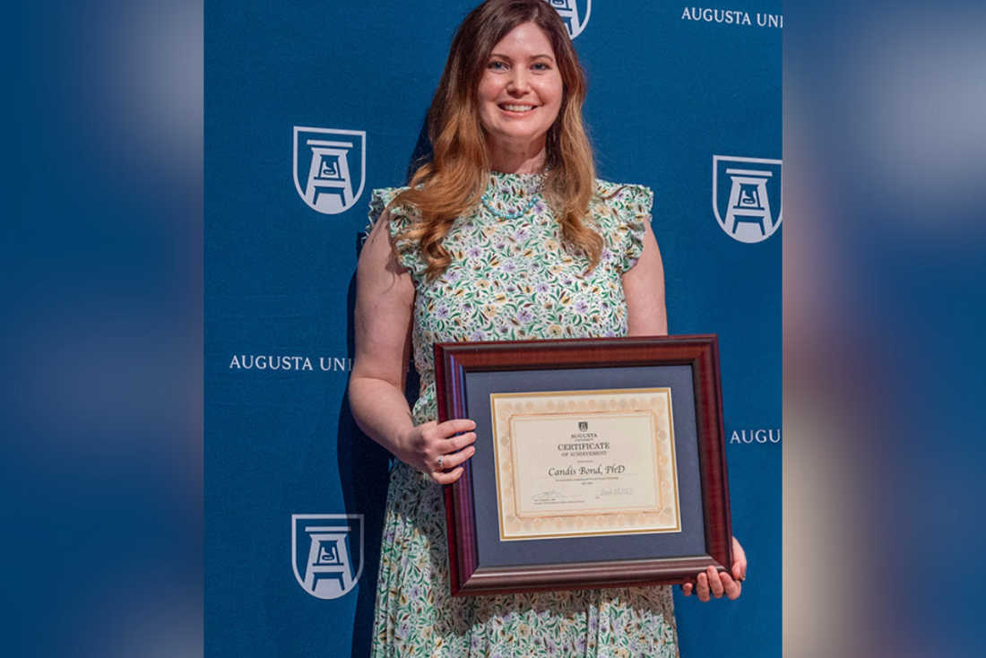 A woman holds up an award.