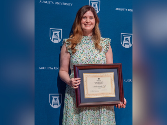 A woman holds up an award.