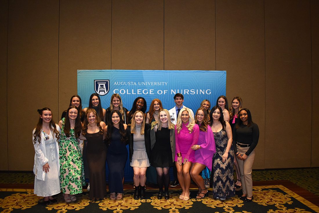 Athens students pose together in front of blue CON step-and-repeat