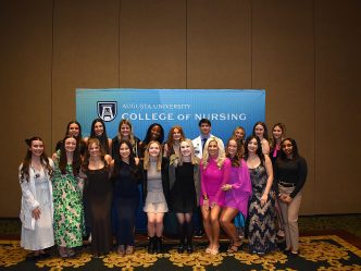 Athens students pose together in front of blue CON step-and-repeat