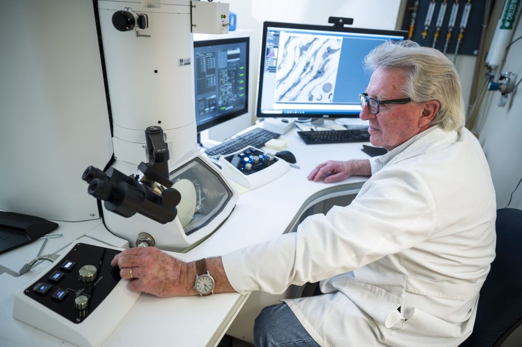 Man using a large microscope with multiple screens in a scientific lab