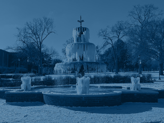 A fountain is frozen with snow all around on the ground around it.