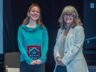 Two women stand together. One is holding a plaque.