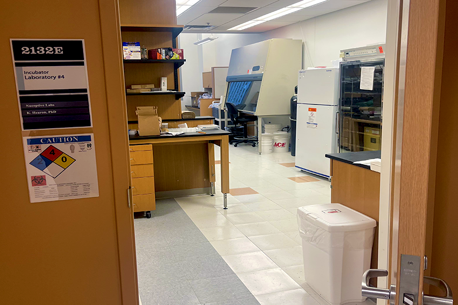 An open door showing a glimpse of a scientific wet lab behind it. There is a sign reading "Nuceptive Labs, K. Hearon, PhD."