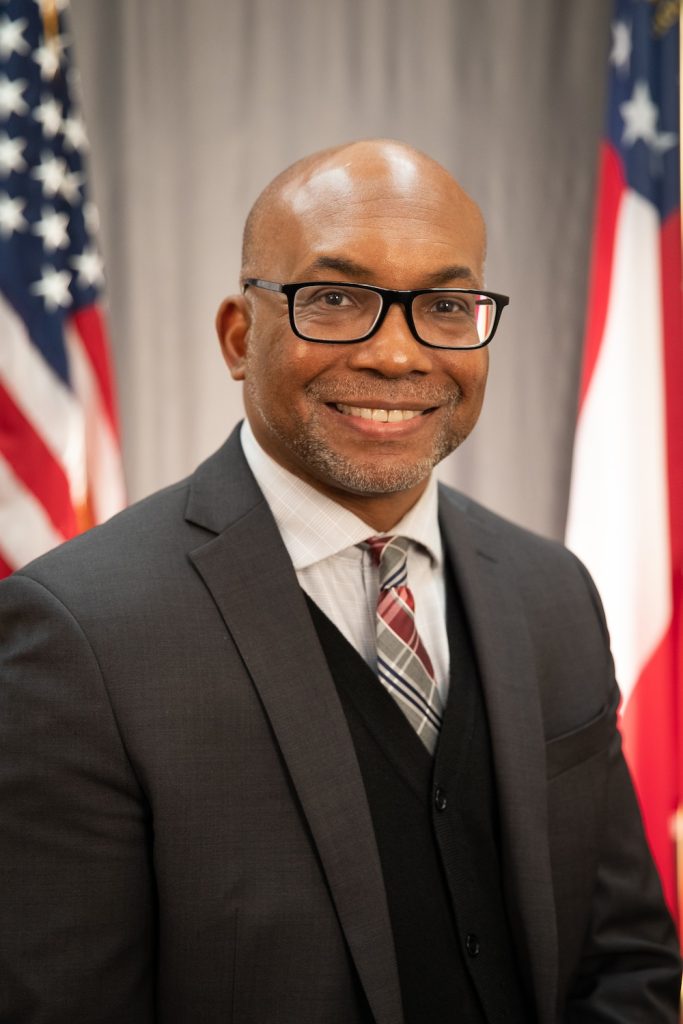 Man in a suit standing in front of the American flag